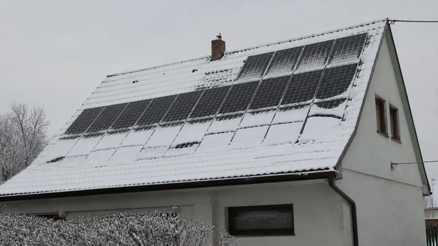Zimná strecha so solárnymi panelmi čiastočne pokrytými snehom